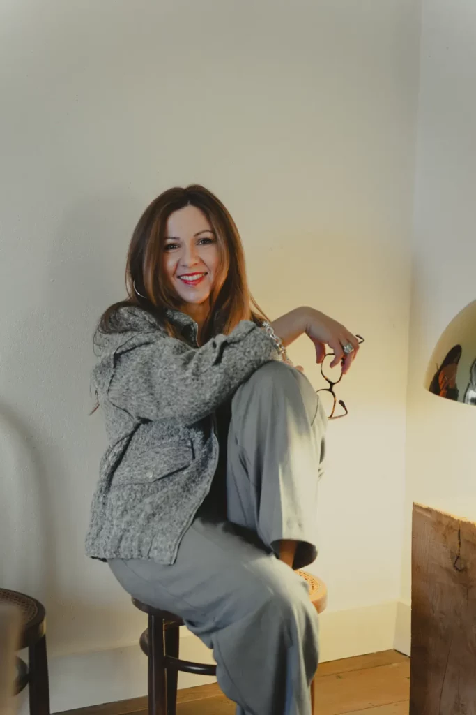Marie-Laure Madeleine souriante, assise sur un tabouret dans un intérieur lumineux