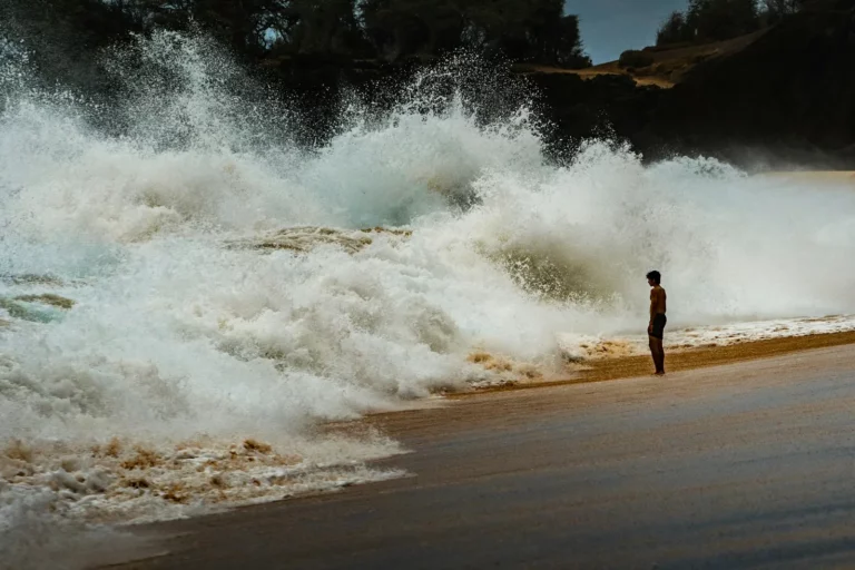 Une silhouette minuscule sur une plage, à côté d’une vague immense qui se brise